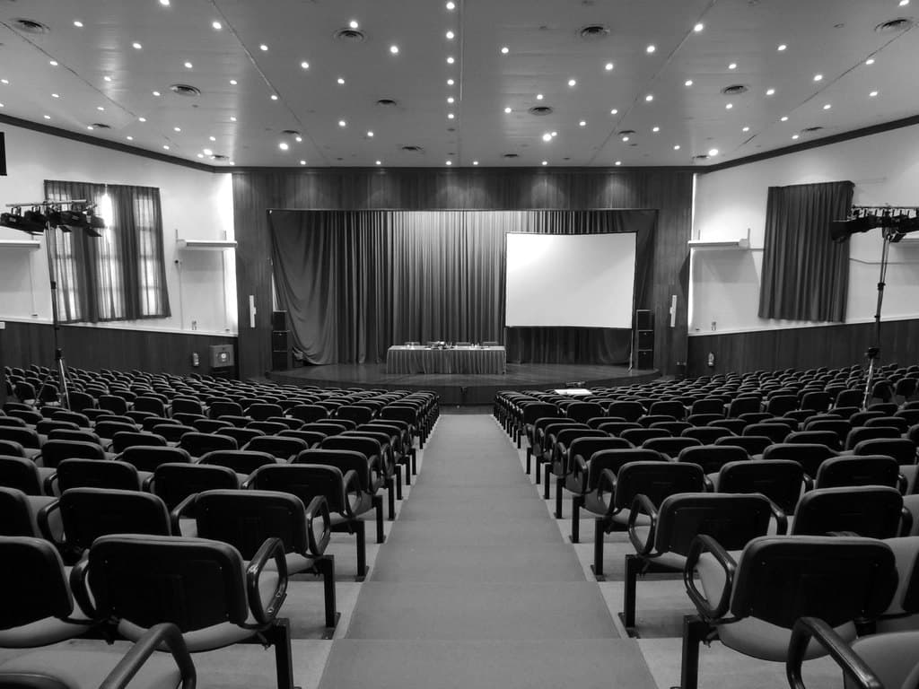 An empty auditorium facing a stage and projection screen