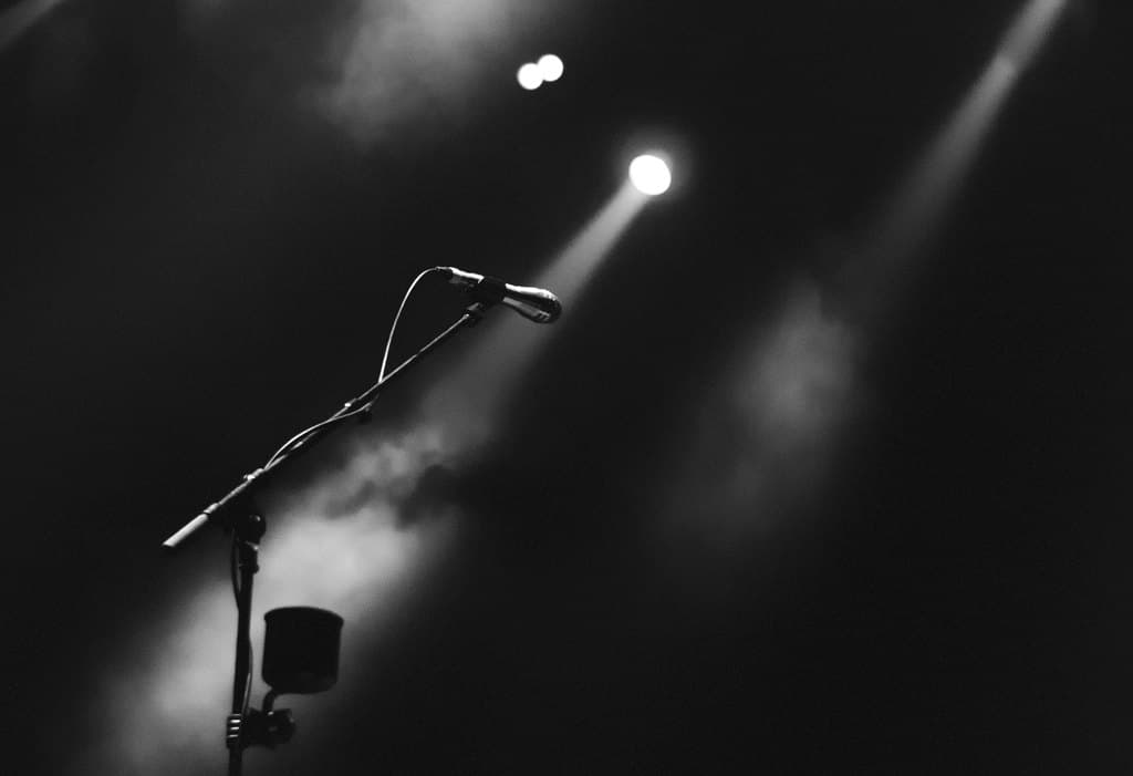 A microphone on an empty stage under a spotlight